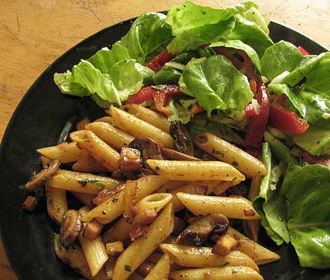 Gebratene Nudeln mit Tofu, Pilzen, Zwiebeln und Salat. 